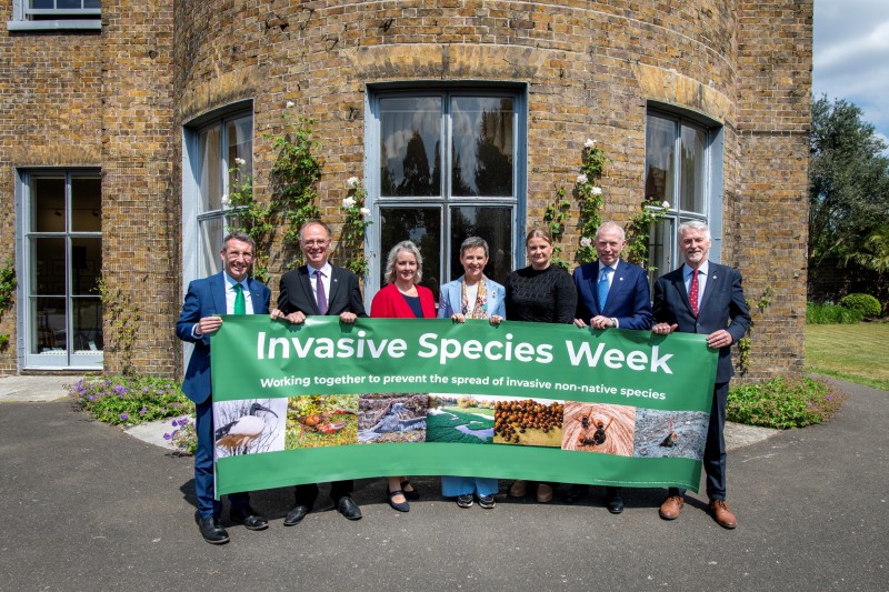 A group of people holding a banner saying 'Invasive Species Week'
