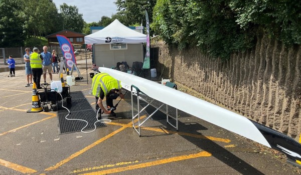 A person jet-washing a rowing boat 